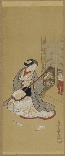 An actor in female dress stringing a samisen