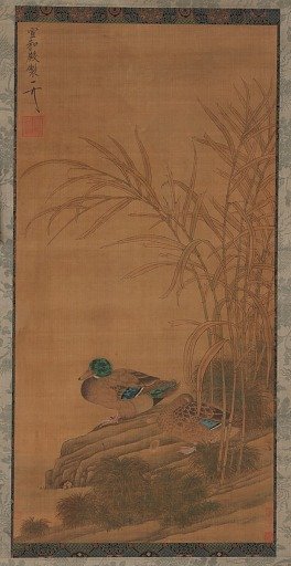 Two ducks among reeds at the water's edge