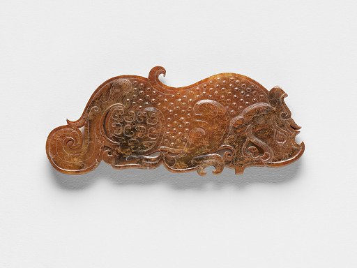 Pendant in the form of a dragon with dragon elements and raised uniform curls arranged in a grid, one of a pair