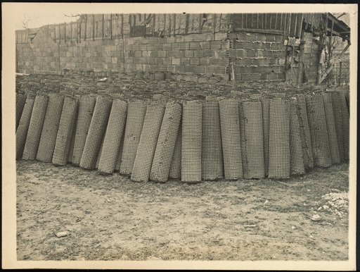 Rolled-up mats leaning against a shed