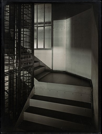 Staircase with a caged elevator shaft and metal steps