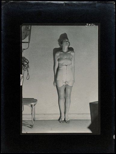 Standing young woman in a corset, advertising photograph for clothing company "P.M.H."