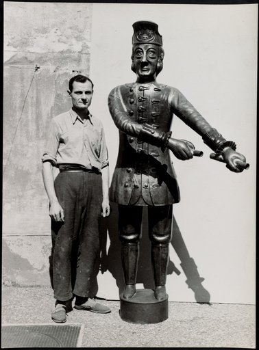 Man next to metal sculpture (male figure in historical costume)