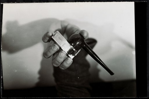 Man's hand with tobacco pipe and metal object