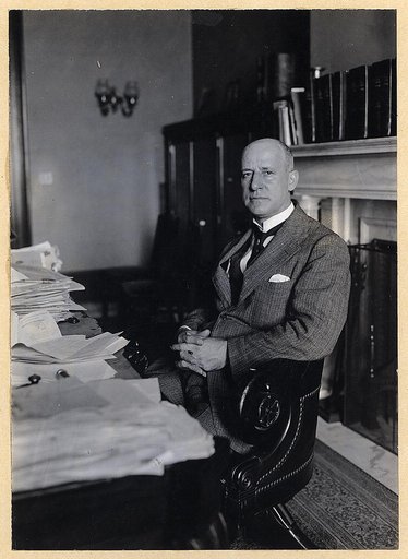 Miles Poindexter, three-quarter length portrait, seated at desk, facing left