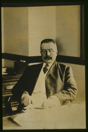 George B. Cortelyou, half-length portrait, seated at desk, facing front