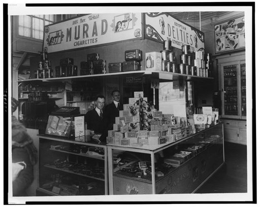 Interior of People's Drug Store, 7th and K Streets, Washington, D.C., with employees behind counter with display of smoking products including pipes, cigars, tobacco, and cigarettes