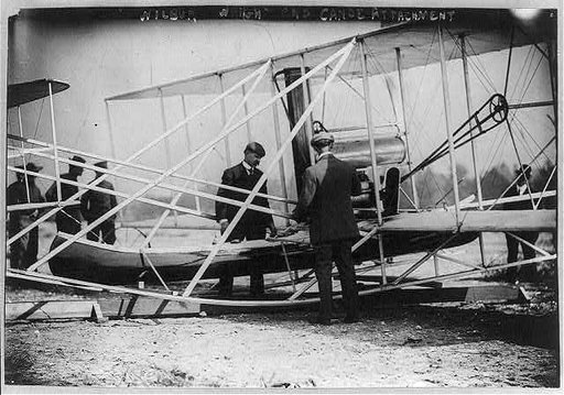 Wilbur Wright examining canoe attachment to aeroplane before 1st flight over water