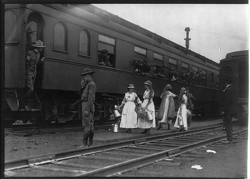 Men on troops train, with Red Cross workers in front, probably in Washington, D.C.