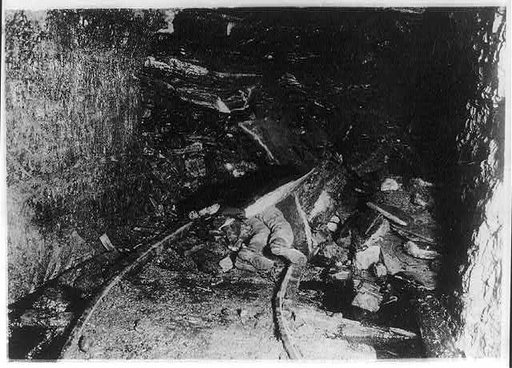 Dead (?) coal miner under rock after cave-in in tunnel