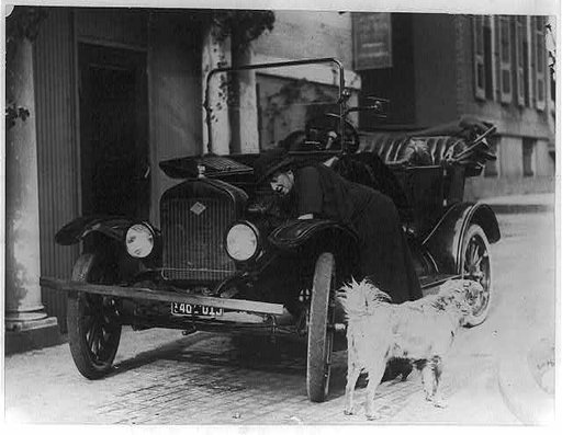 Miss Maude Younger of San Francisco, Legislative Secty. of the National Womans Party, who has arrived in Washington to attend the Convention of the Womans Party, working on her Ford car - her dog, Sandy, is in the foreground