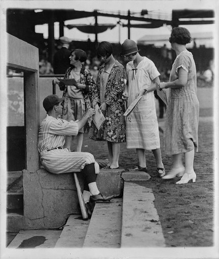 Bucky Harris autographing scorecards on dugout steps, on Ladies Day