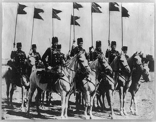 8 members of the Turkish cavalry on horseback with flags