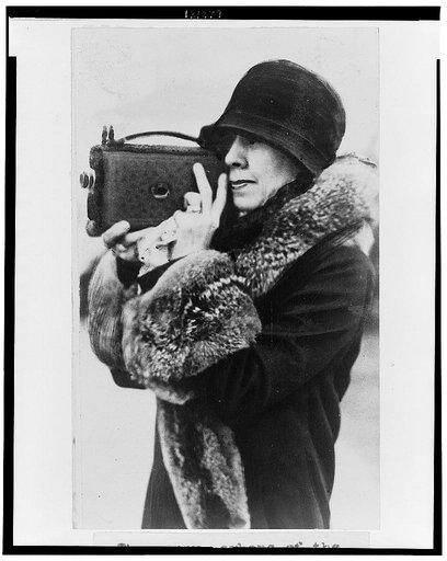Mrs. Coolidge, member of the White House News Photographers Association, half-length portrait, standing, facing left, holding camera up to face