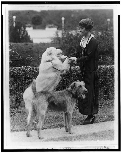 Grace Coolidge with two dogs, holding the front paws of one