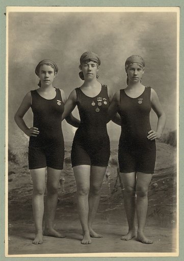 Three young women posing in swimsuits and wearing their swimming competition medals