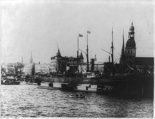 View of Riga, Latvia with waterfront in foregrd; freighter ERIK and lumber barges