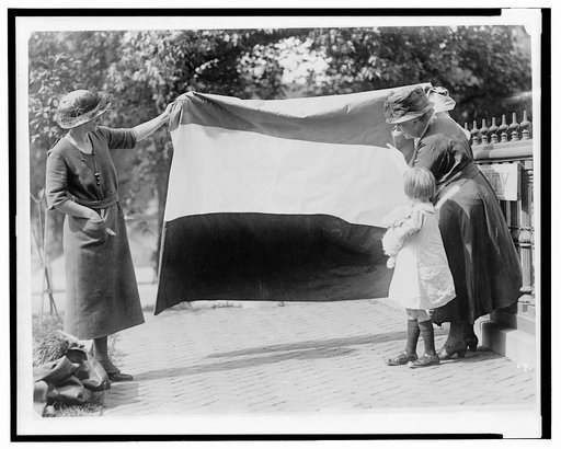 Two suffragists showing banner to young girl