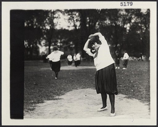 A women's softball baseball game showing a woman on the pitcher's mound about to pitch the ball
