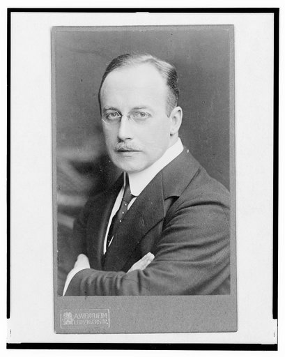Dr. Jos. Fischer, half-length portrait, arms crossed over chest, facing left