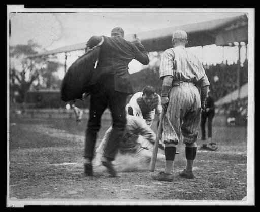 Umpire making the call on a man sliding into home plate during a baseball game between Washington and the Boston Red Sox