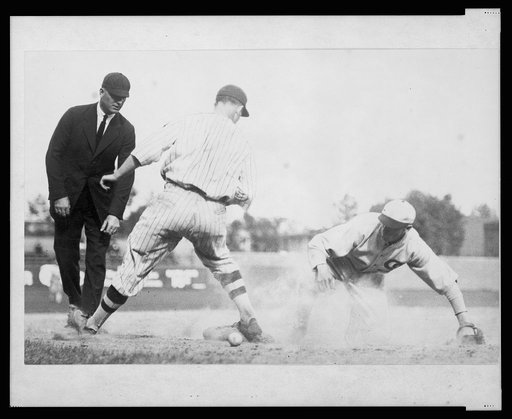 Umpire ready to make the call as base runner reaches 3rd base safely when the ball gets away from the third baseman