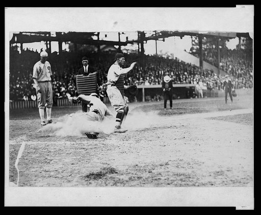 Umpire watches as base runner slides into home plate ahead of the tag during baseball game