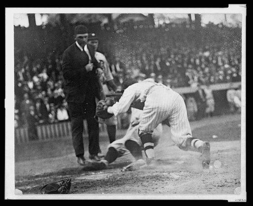 Umpire ready to make the call as catcher tags base runner sliding into home plate during baseball game