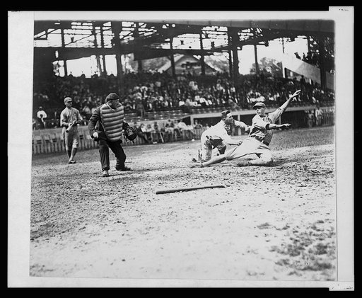 Umpire makes the call as the catcher applies tag to ball player sliding into home plate during a baseball game