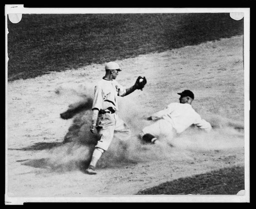 Ball player sliding into base as fielder reaches to apply tag during baseball game