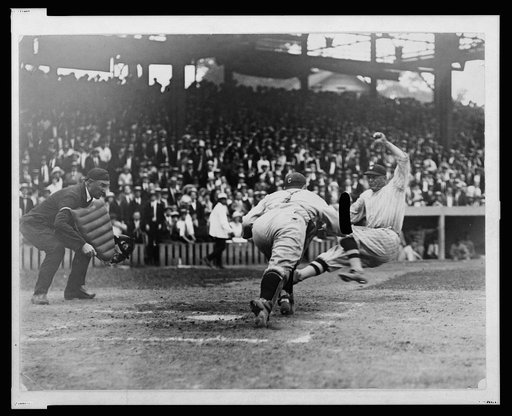 Umpire ready to make the call as catcher lunges to apply tag to Washington ball player sliding into home plate during baseball game