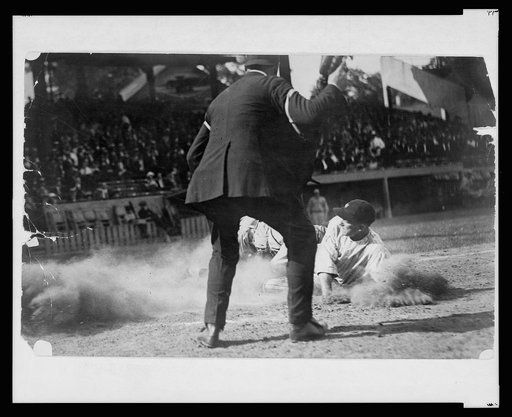 Umpire ready to make the call as Washington ball player slides into home plate during baseball game