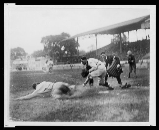Umpire ready to make the call as Washington catcher reaches with ball in hand to make the tag on ball player sliding into home plate during baseball game