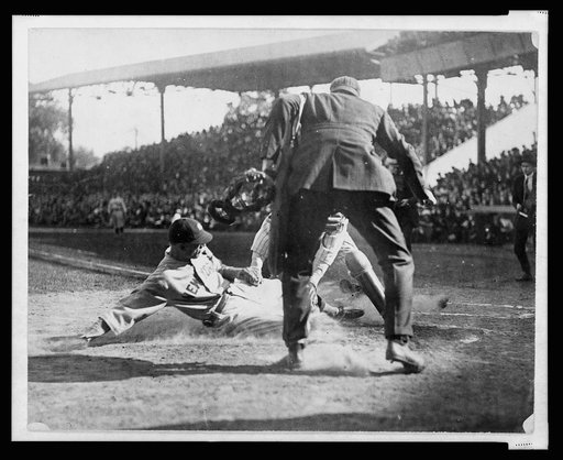 Umpire gets ready to make the call as catcher applies tag to New York Yankee ball player sliding into home plate during baseball game