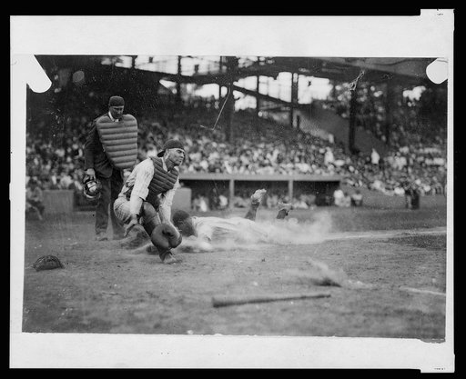 Umpire Nallan ready to make the call as Washington catcher Hank Severeid awaits ball while New York Yankee Lou Gehrig slides into home plate during baseball game