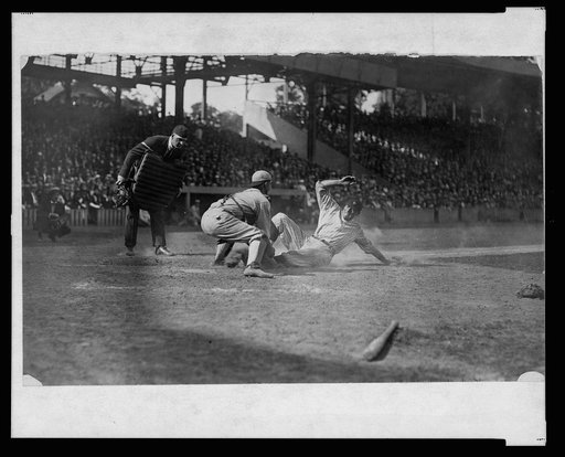 Umpire ready to make the call as catcher applies tag to Washington ball player sliding into home plate during baseball game
