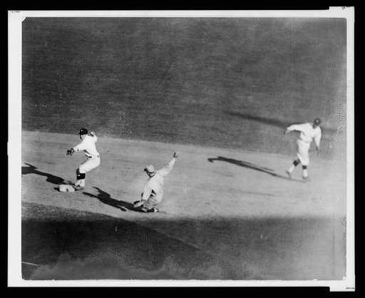 Washington fielder tags second base ahead of sliding base runner and turns to throw ball to first base to complete a double play during baseball game