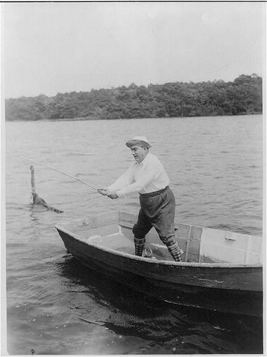 Enrico Caruso, 1873-1921, full-length portrait, standing, facing left, in boat, at his home, Easthampton [i.e., East Hampton?], fishing, using stick as fishing rod(?)