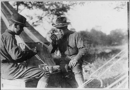 News photos of N.Y. National Guard units preparing for active duty on Mexican border, May-Nov. 1916: 2 soldiers eating outside tent at Van Cortlandt Park