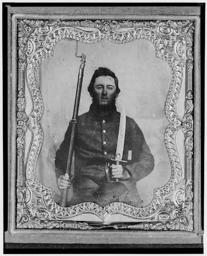 Thomas Kitchen, Pvt., Georgia regiment, C.S.A., three-quarter length portrait, seated holding bayonet and rifle, facing front