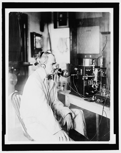 Lee DeForest, 1873-1961, half length portrait, seated with one of his inventions, facing right