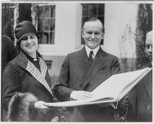 Pres. Coolidge receiving a book containing oil paintings of scenes in Mackinac Island and a complete history of the island, on which he is being invited to spend the summer, from Mrs. W.W. Wittinghill of Detroit, as official representative of Gov. Green of Michigan
