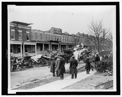 Men watching debris being cleaned up at row houses on A St., NE, near 14th St., severely damaged by a tornado on Nov. 17, 1927