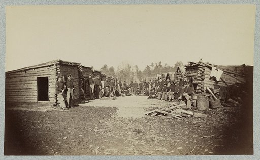 Union soldiers, in camp, posed in front of log buildings
