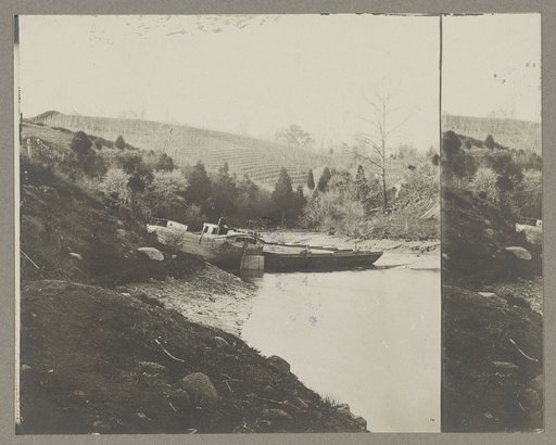 Boats docked at the shore of a river in a wooded area