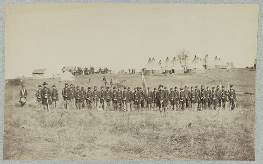 Union soldiers lined up in the field with tents in the background