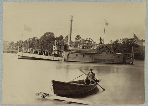 A sailor sits in a small boat in the foreground with a side wheeler in the rear