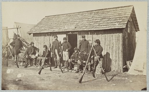 Soldiers outside a log cabin winter quarters, identified as "Pine Cottage"