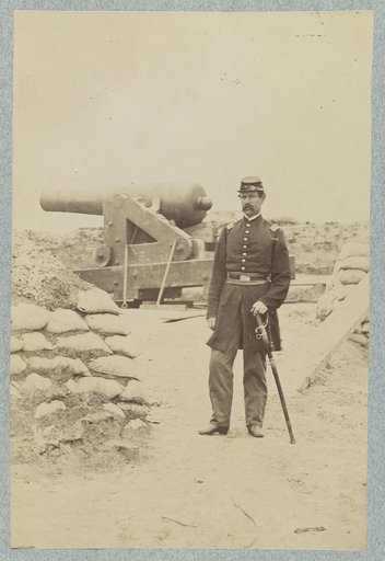 Union officer standing in an unidentified fort in front of a cannon