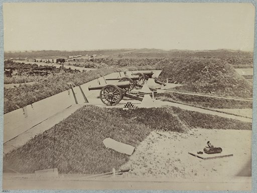 Mounted guns and ammunition around the perimeter of a fort, and tents in the background